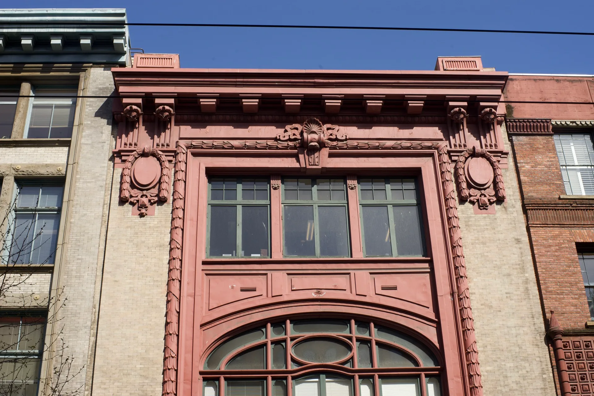 Ornate red terracotta building facade in Pioneer Square, Seattle, arched windows and decorative ironwork against blue sky