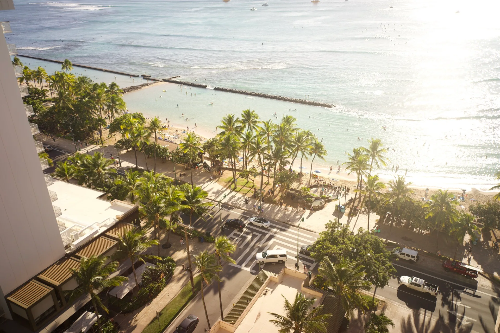 Golden afternoon light spilling down the side of the hotel onto palm-lined Kalakaua Avenue and the beach below
